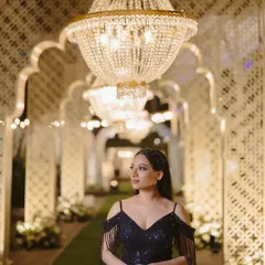 A glamorous portrait of the bride under a canopy of crystal chandeliers. This grand entryway was designed to make a statement, bathing the reception hall in warm, sparkling light.