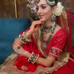 A side profile showcasing the elegant green passa and matching earrings. This angle also gives a great view of the intricate haath phool and bangles, all part of the rental set.