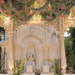 A closer look at the mandap seating, featuring ornate silver chairs against a backdrop of intricate white latticework. The floral canopy above added a layer of softness and romance to the regal design.