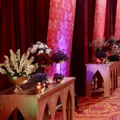 A closer look at the decor along the entrance walkway. Wooden console tables with arched designs held beautiful floral arrangements in brass vases, adding to the regal theme.