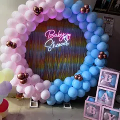 This half-pink, half-blue balloon ring is perfect for a baby shower or gender reveal. The setup includes a "Baby Shower" neon sign, a shimmer curtain backdrop, and matching 'BABY' blocks.