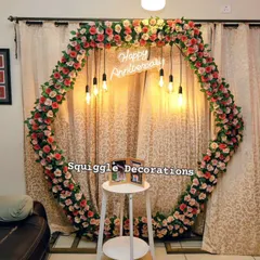 A beautiful hexagonal floral arch created for an intimate anniversary celebration at home. The warm lighting and personalized 'Happy Anniversary' sign create a romantic photo corner.