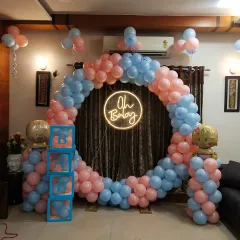 I can transform any room in your home into a beautiful celebration space. Here, I created a classic pink and blue circular balloon arch with an "Oh Baby" neon sign, perfect for an intimate at-home baby shower.
