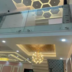 A unique view looking up through a glass floor to a hexagonal-patterned false ceiling on the upper level. This bold design choice allows light to travel between floors and creates a dramatic architectural feature.