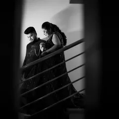 A dramatic black and white photo of a couple on a staircase during their Sangeet night, framed through railings for an artistic effect.