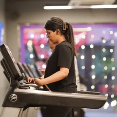 A member focuses on her run, using one of the many treadmills available in our spacious cardio section.
