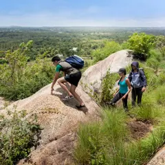 A group of friends trekking over the rocky terrain near our Nandi Hills location. Our guided hikes are a great way to get active and enjoy panoramic views.