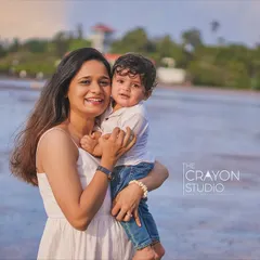 A mother holds her son close, her smile radiating pure love and happiness. This candid portrait by the sea is a beautiful testament to the strong bond they share.