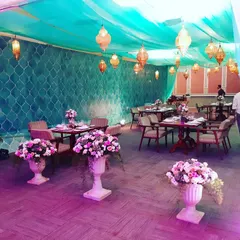 Another view of our themed dining setup. The combination of ambient lighting from the hanging lanterns and the colorful floral arrangements creates a warm and inviting space for guests to dine and socialize.