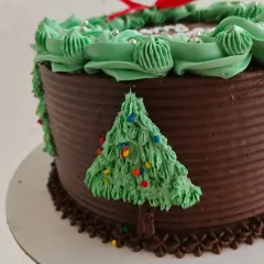 A close-up of the details on my Christmas wreath cake, including the little buttercream Christmas trees on the side. Every element is handcrafted to make your celebration special.