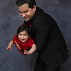 The pure joy on a baby girl's face as her father playfully lifts her up. This studio shot captures the special bond between a father and his daughter.