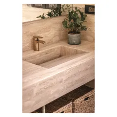 A close-up of the carved travertine sink and bronze tap, showcasing the beauty of natural stone.