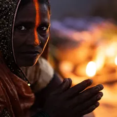 A woman offers her prayers during the Chhath Puja festival in Delhi. The warm glow from the diyas illuminates her face, highlighting a moment of deep, personal faith amidst the communal celebration.