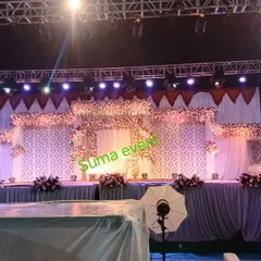 For this large-scale wedding, I constructed a multi-level stage with patterned white backdrops and extensive floral arrangements. The professional lighting setup highlights the intricate details and creates a dramatic effect.