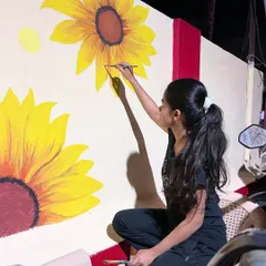 Painting the large yellow sunflowers, making sure they stand out boldly against the deep blue night sky.