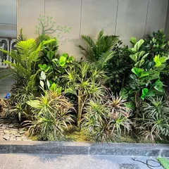 The garden is beginning to take shape. Here you can see the dense layering of different types of artificial foliage, creating a rich and textured look before the final lighting and finishing touches are added.