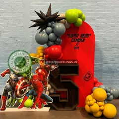 A powerful "Super Hero" setup for a fifth birthday, featuring the Avengers team. The bold red backdrop and a custom-built number '5' shelf for displaying treats make this a standout design.