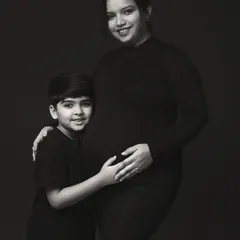 A timeless black and white portrait of a mother and her son. His arm around her, and her hand on her belly, tells a story of love, protection, and new beginnings.