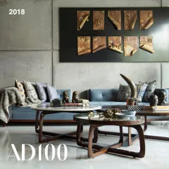 A living room from the Guha Residence, an AD100 project. This space showcases our custom-designed coffee tables and a comfortable blue sofa set against a board-formed concrete wall, balanced by intricate wall art.