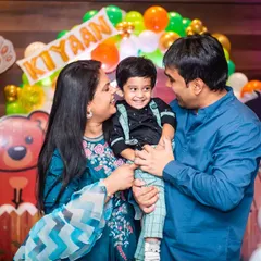 A candid family portrait filled with smiles at a second birthday party with a colorful animal theme.