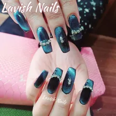 Deep teal cat-eye nails in a coffin shape, embellished with elegant rhinestone bands for a touch of luxury.