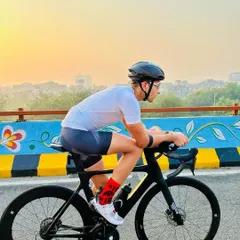 A rider in an aerodynamic tuck position, showcasing proper form for speed and efficiency during a competitive training ride over a flyover.