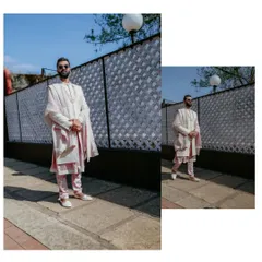A stylish, full-length portrait of the groom in his elegant pastel pink and white wedding attire.