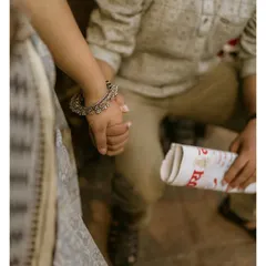 A detailed shot of a couple holding hands, with a rolled-up newspaper as a prop. This close-up highlights the simple, meaningful gestures of an old-school romance.