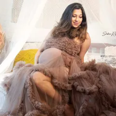 This mom-to-be looks absolutely radiant in this ruffled gown, sitting in our bohemian-themed setup. The soft textures and earthy tones create a warm and artistic feel for her solo maternity portrait.