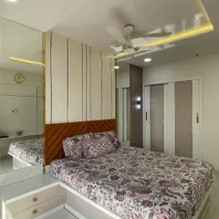 A bright and airy bedroom featuring a mirrored wardrobe that visually expands the space. The combination of a patterned headboard and subtle ceiling lights creates a sophisticated look.