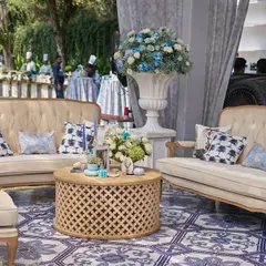 I designed comfortable and stylish lounge areas with beige tufted sofas, patterned cushions, and carved wooden tables, all set upon the beautiful blue-and-white tiled floor.