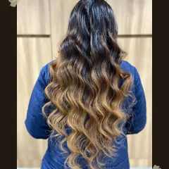 This is the sunkissed look everyone dreams of. We created this beautiful balayage on long hair, blending dark roots seamlessly into warm, golden ends and finishing with soft waves to show off the dimension. This is a perfect example of our custom hair highlighting services.