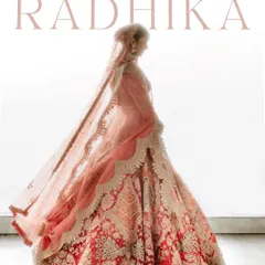 A breathtaking shot of Radhika, showcasing the magnificent trail of her bridal lehenga. The backlighting creates a beautiful silhouette, emphasizing the grandeur and elegance of her entire look.