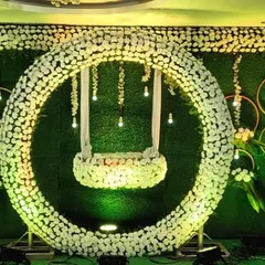 For a grand naming ceremony, we designed this stunning floral ring with a hanging cradle. This modern setup against a lush green wall creates a dramatic and beautiful centerpiece for the event.