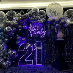 For this 21st birthday, we went for a chic and modern party vibe. The centerpiece is the glowing neon signage, including the age and a 'Let's Party' sign. I paired it with a dramatic backdrop of a silver tinsel curtain and a cascade of chrome and confetti balloons for a truly stylish celebration.