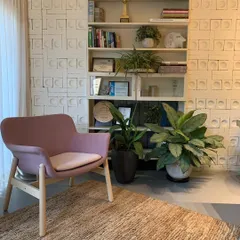 This cozy reading corner in our studio features a repurposed bookshelf set against a textured wall. By adding indoor plants and comfortable seating, we created a biophilic space that feels both elegant and calming.
