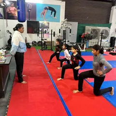 A coach leads a group of young girls through a lunge exercise. We teach proper form for fundamental fitness movements to build a strong athletic base.