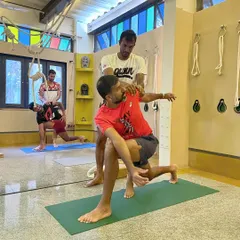 Working with a professional tennis player on a deep lunge with a twist. This pose targets hip flexibility and thoracic spine mobility, key areas for generating power and maintaining agility on the court. The adjustment helps ensure proper form to maximize benefits.