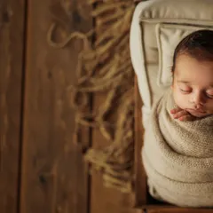 A wider perspective of this rustic setup, showing the beautiful wooden textures and jute rug that complement the simple, earthy wrap. This style creates a warm and timeless feel for your baby's first portraits.
