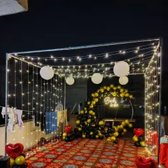 A custom 'Bride to be' neon sign adds a modern and trendy touch to this bachelorette party setup. It serves as a great photo prop within the fairy light canopy.