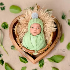 Wide-eyed and wonderful. This alert newborn looks directly into the camera from his cozy, heart-shaped basket, showing a glimpse of his curious little personality.