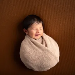 A simple "potato sack" swaddle is perfect for capturing those sleepy smiles. With all distractions removed, the focus is entirely on the baby's happy expression.