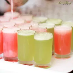 A tray of vibrant welcome drinks being prepared. I offer a variety of fresh juice shots, like watermelon and cucumber mint, to give your guests a colorful and refreshing start to the event.