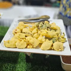 A platter of assorted vegetable pakoras, crispy and golden brown. Served with tangy chutney, these are the perfect comfort food and a crowd-pleaser for any celebration, especially during monsoon weddings.