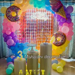 A sweet treats theme for a third birthday. This colorful setup includes a circular balloon arch, a shimmer backdrop, large donut and ice cream foil balloons, and a light-up number '3'.