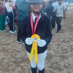 The smile of a champion. This young rider proudly displays her ribbon after a great performance, showing the joy that comes with equestrian sports.
