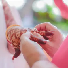 A close-up of the ring exchange ceremony. This shot focuses on the hands, the intricate mehendi, and the wedding ring, symbolizing the official union of the couple.