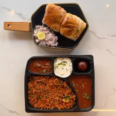 This meal box showcases a popular combination of Tawa Pulao and Pav Bhaji, served with raita and gulab jamun. It's a convenient, no fuss option for feeding a group with individual portions.