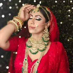 This shot captures the elegance of a bride in a red saree, adorned with a full Kundan and emerald jewellery set. The sparkly backdrop is one of many options available at the studio.