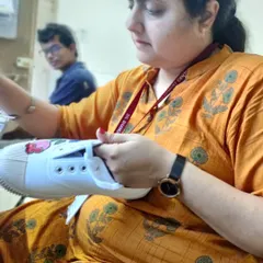 A participant fully engaged in painting her sneaker. My workshops are hands-on, providing a relaxed space where you can learn painting techniques and apply them directly to your own stuff. No experience needed.
